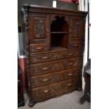 A large late 19th/early 20th century carved oak cabinet, the upper section with central shelved