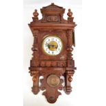 An early 20th century oak cased wall clock, the carved detail surrounding a circular dial set with