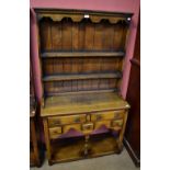 A small reproduction oak dresser, the plate rack back with two fixed shelves above an arrangement of