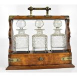 A late 19th/early 20th century oak tantalus with silver plated mounts housing three clear hobnail