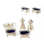 A George V hallmarked silver cruet set of baluster form with gadrooned and shell borders comprising