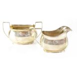 A George V hallmarked silver milk jug and sugar bowl, both monogrammed 'BJ' to the front,