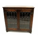 An early 20th century glazed bookcase with carved decoration to the frieze,