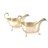 A pair of George V hallmarked silver sauce boats with piecrust edge and double C-scroll handles,