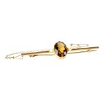A Victorian yellow metal bar brooch with oval smoky quartz flanked by two small seed pearls and