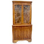 A reproduction yew wood double-fronted freestanding corner cupboard with dentil moulded cornice