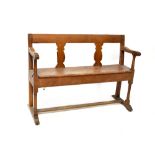 A 19th century oak bench with vase splats and open arms, on turned legs and stretchered supports,