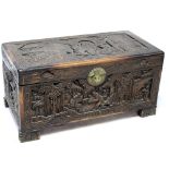 An Oriental camphor wood blanket box, heavily carved with village and figural scenes, length 86cm.