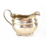 A George III hallmarked silver cream jug of banded baluster form with gadrooned edge and acanthus