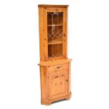 A pine freestanding corner cupboard with glazed upper section above panel door, height 184cm.
