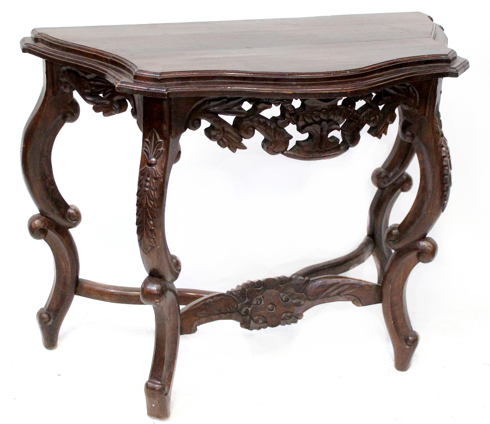 A reproduction hardwood console table, serpentine top on C-scroll and heavily carved base,