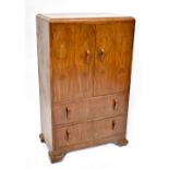 A 1930s walnut veneered tallboy with pair of cupboard doors above two long drawers,