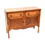 A c1930s oak sideboard, two frieze drawers over two cupboard doors with raised carved decoration,