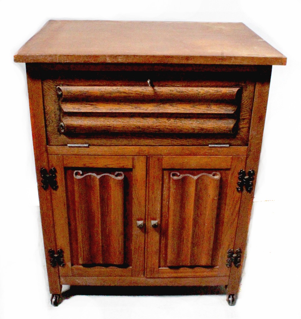 An early 20th century oak side cabinet with small fall-front section above pair of linen fold
