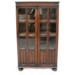 An early 20th century oak Priory-style display cabinet with pair of glazed doors with linen fold