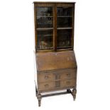 A 1930s oak bureau bookcase with glazed upper section, egg and dart carved frieze,