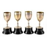 Four small silver trophy chalices and lacquered bases,