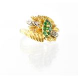 An 18ct gold, emerald and diamond flower and leaf cross-over ring,