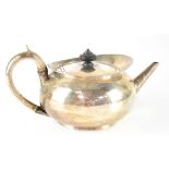A George III hallmarked silver teapot of oval form with loop handle and hinged cover with turned