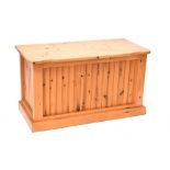 A contemporary pine chest, shaped lift-up lid over panelled front to plinth base, length 94cm.