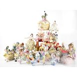A quantity of porcelain and bisque half dolls, porcelain figures with lace dresses and pincushions.
