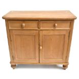 A late Victorian pine side cabinet with moulded top over two drawers and two cupboard doors raised