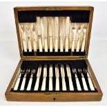 An oak cased set of twelve mother of pearl handled and silver plate bladed fruit knives and forks.