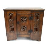 An oak Gothic 15th century style aumbry with rectangular mounted top above single door pierced