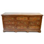 A late George III oak and pollard oak crossbanded nine drawer dresser base with moulded three