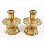 A pair of Arts & Crafts brass, green and white enamel decorated candlesticks with stylised floral