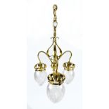 An Arts & Crafts brass three branch ceiling light with scrolled detail and three clear glass