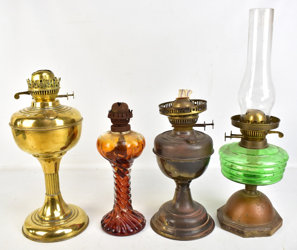 Four vintage oil lamps, one with green glass reservoir, one all brass and one with amber tinted