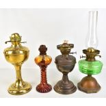 Four vintage oil lamps, one with green glass reservoir, one all brass and one with amber tinted