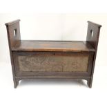 An Arts & Crafts carved oak bench with applied copper plated panel featuring embossed floral