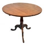 A late George III oak tilt top circular tripod occasional table raised on three outswept supports,