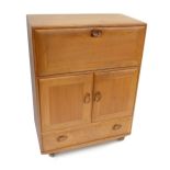 ERCOL; a light elm Windsor drinks cabinet with pull down door above two panelled cupboard doors