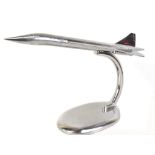 A large modern polished aluminium model of Concorde, raised on swept support to oval base, length