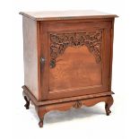 A 20th century stained wooden cupboard with carved door and serpentine frieze,