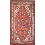 A hand-knotted Persian Hamedan (Iranian) carpet, red ground with ivory border, 290 x 210cm.