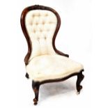A Victorian walnut nursing chair with carved scroll and foliate motif,