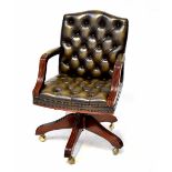A mahogany-framed green leather Chesterfield-style swivel office chair.