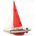 A large red, yellow and cream pond yacht, deck adorned with various plastic and ceramic animals,