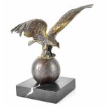 A bronzed figure of an eagle standing on a globe raised on square section base, height 24cm.