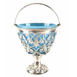 A Victorian hallmarked silver pierced basket with swing handle and pale blue glass liner,