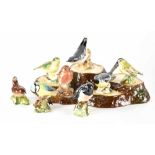 A Beswick tree stump stand and a collection of nine small birds to include 980 'Robin',