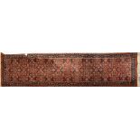 A terracotta ground hand-knotted Persian woollen runner with central panel of flora and fauna