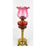 A Victorian oil lamp with associated crimped cranberry glass shade, clear glass chimney, ruby