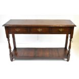 A reproduction oak console table with three drawers above under tier, raised on bun feet, height