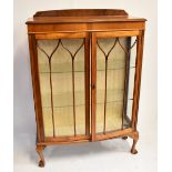 An early to mid-20th century walnut and stained beech twin door glazed display cabinet of slightly