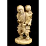 A Japanese Meiji period carved ivory okimono of a gentleman carrying two fish with a child upon